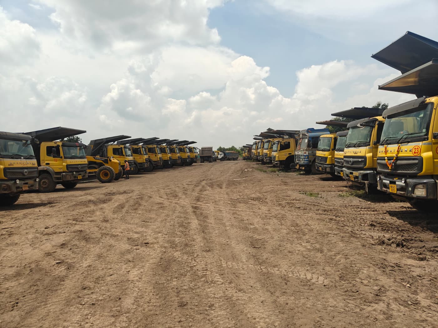 Long line of Shree Sai Construction tipper trucks parked along a haul road