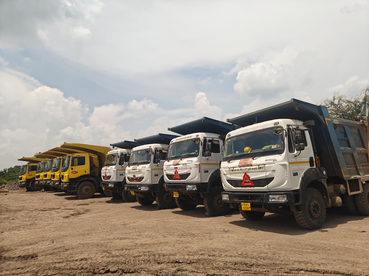 Row of tipper trucks and dumpers staged at an opencast mining site